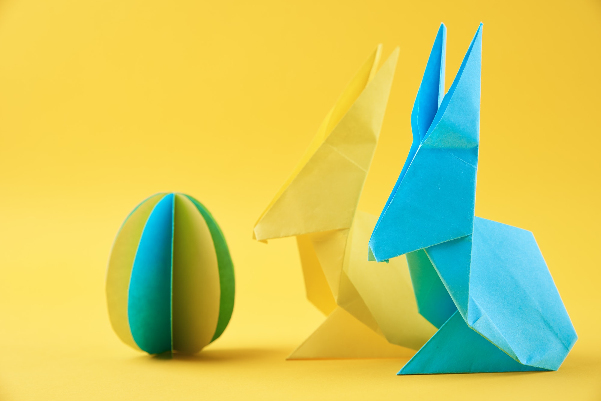 two paper origami esater rabbits and colored egg on yellow background easter celebration concept 1